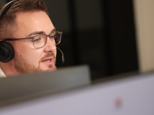 Layer 4 engineer wearing a headset, providing IT support to a coach operator