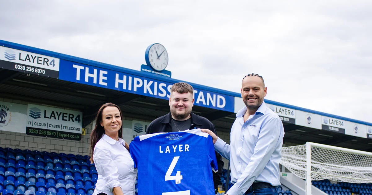 Layer 4 colleagues with Chester FC General Manager holding a Chester FC shirt after signing a three-year commercial partnership