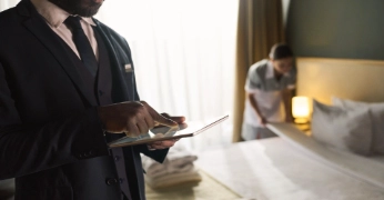Hotel employee using a tablet while a room is prepared