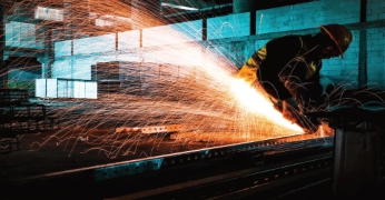 Manufacturing worker cutting metal in a factory