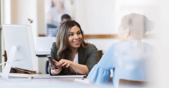 Professional services adviser speaking with a client at her desk